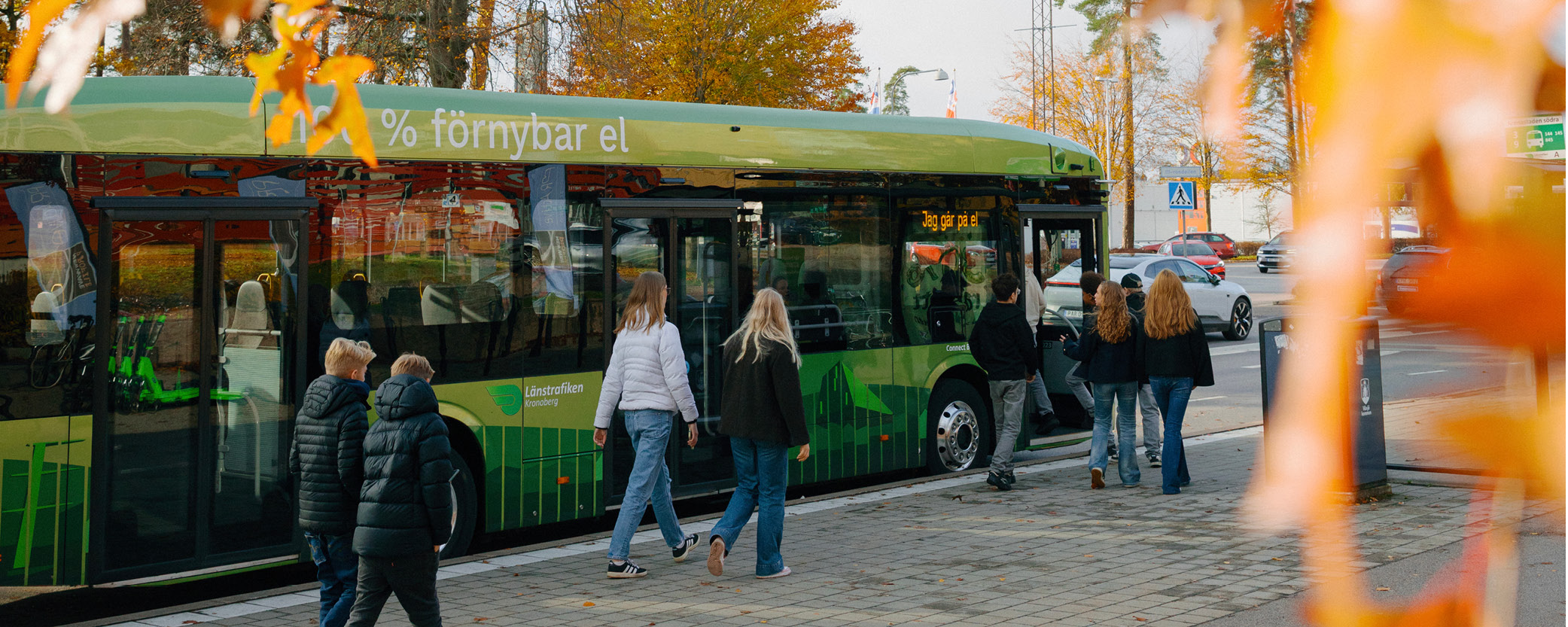 Ungdomar går utmed en buss. Det är höst.